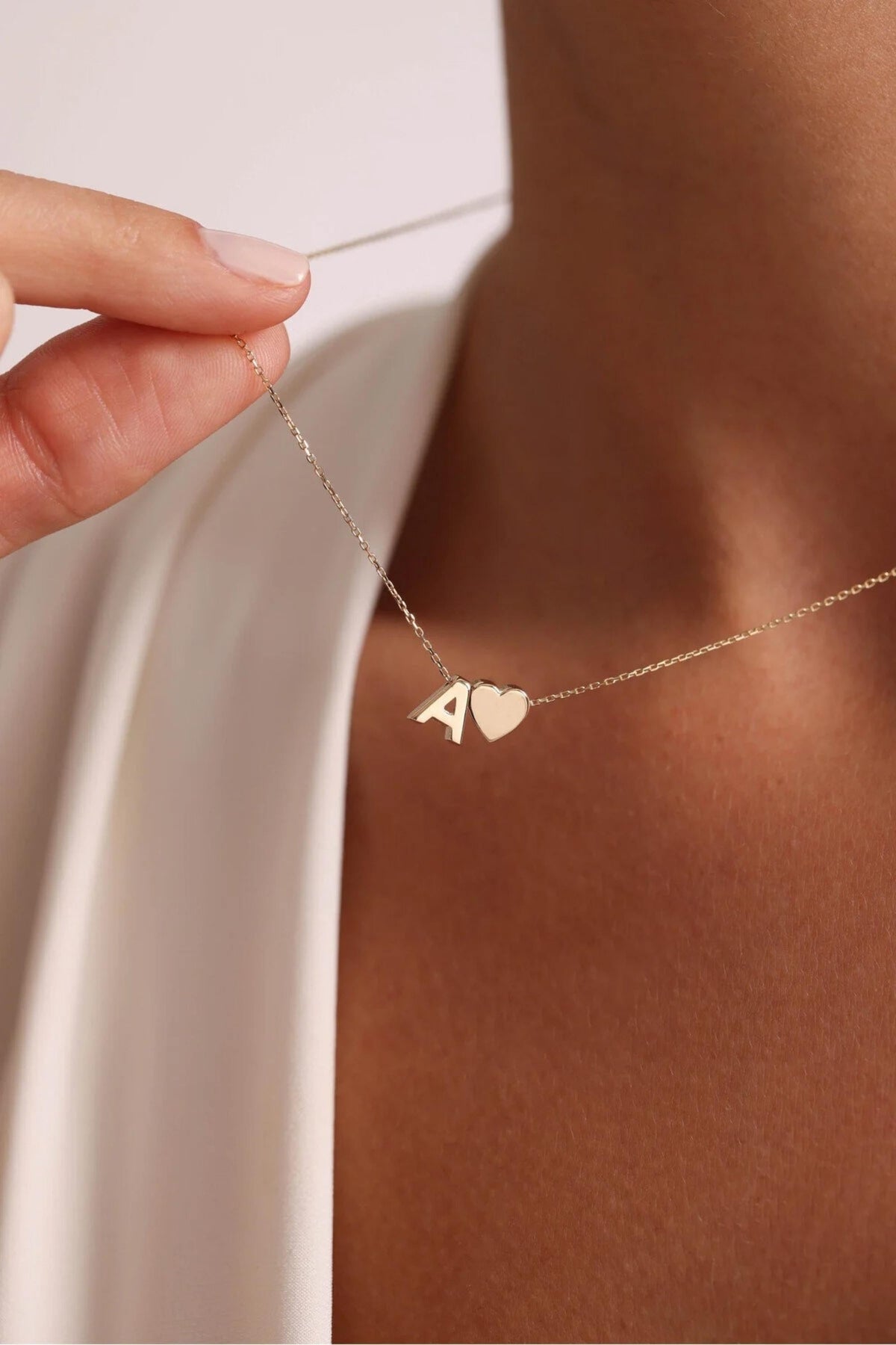 14K gold initial and heart necklace worn at the collarbone
